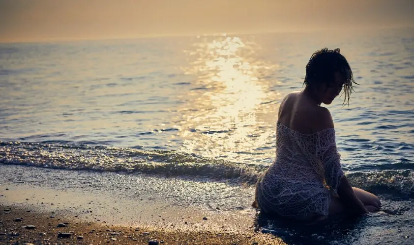 woman sitting grounding her body on the beach